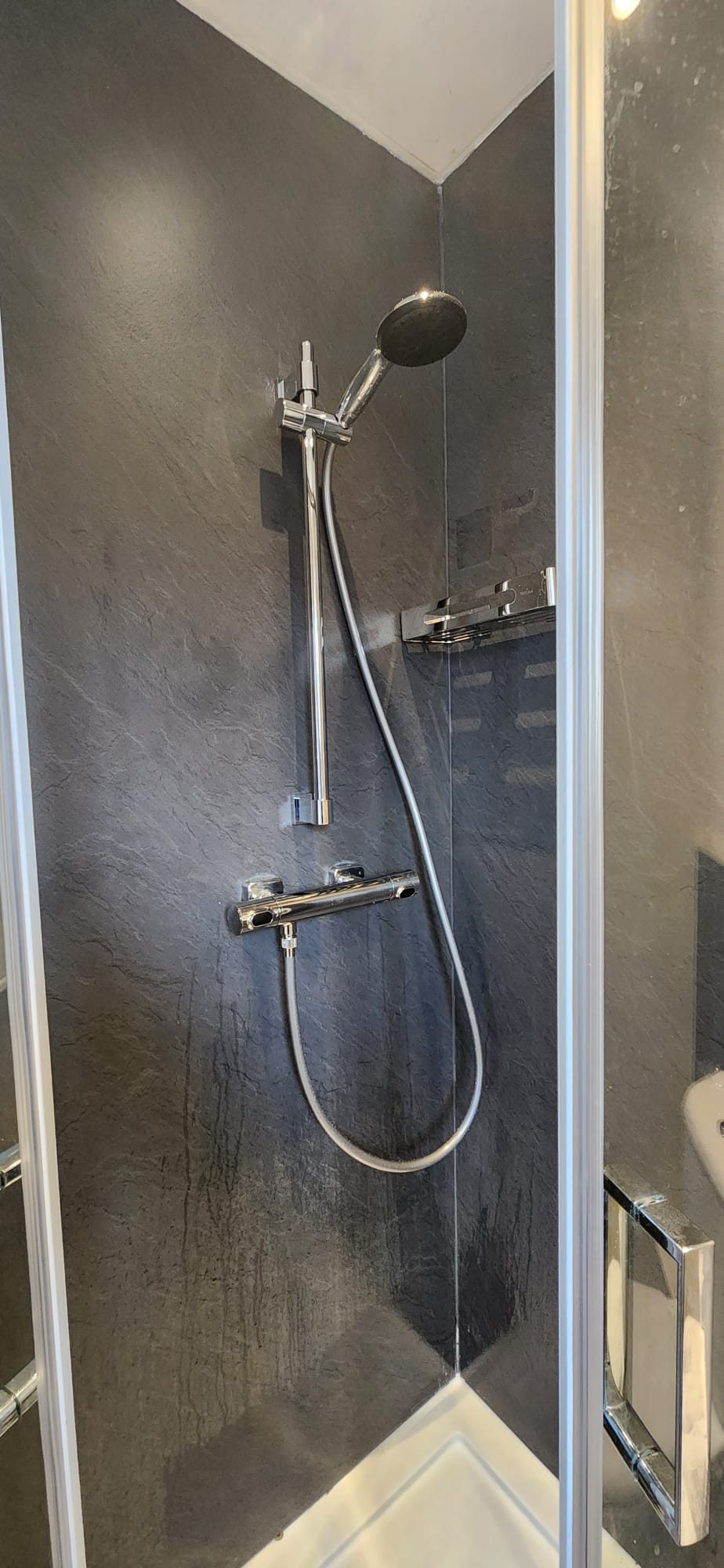A newly fitted chrome shower with slate-effect panelling